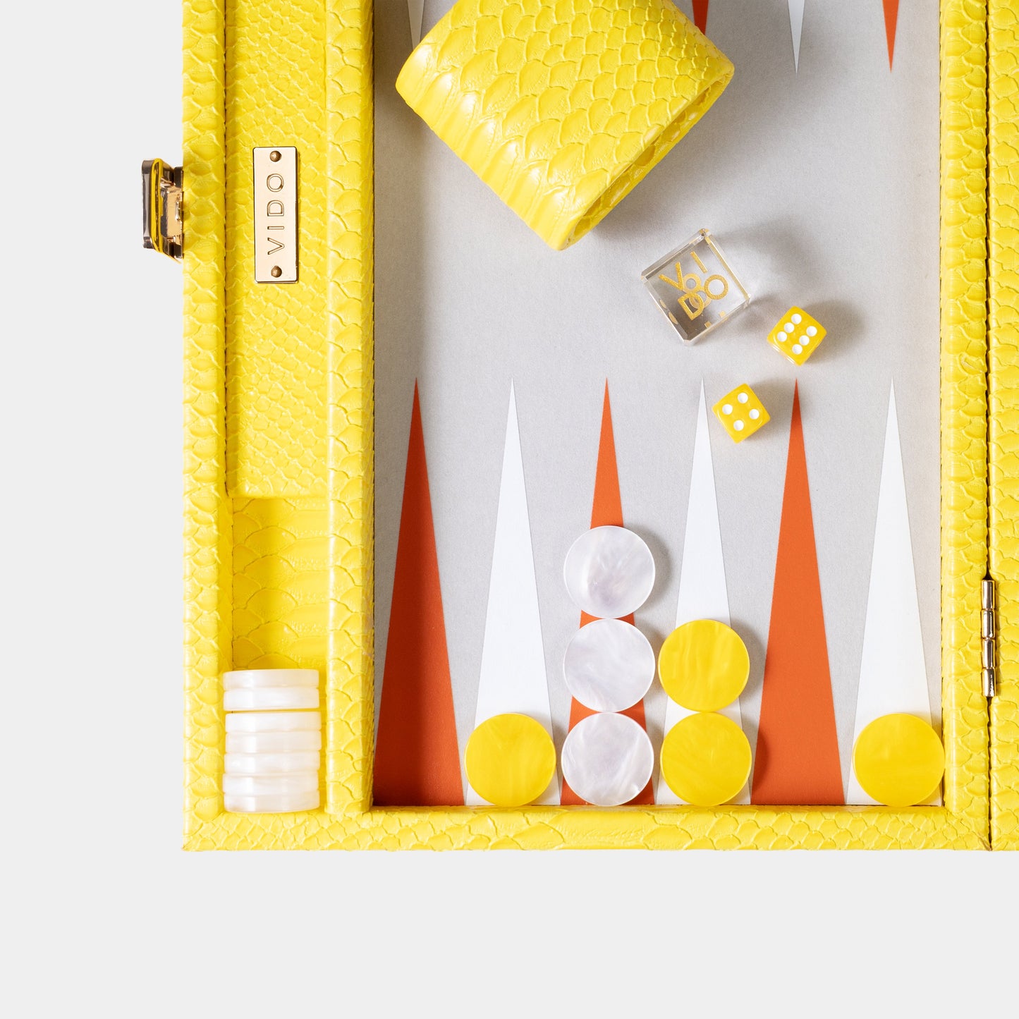 Yellow backgammon box with checkers, dice, and game pieces on a white background by VIDO